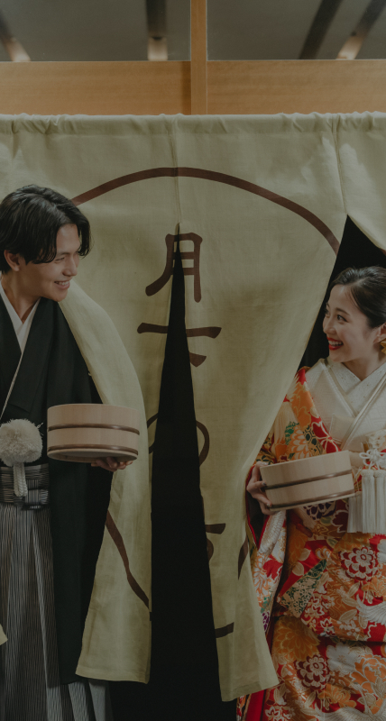 写真：銭湯ののれんを潜る和装の新郎新婦